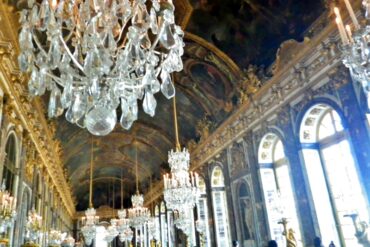 A chandelier hanging between mirrors